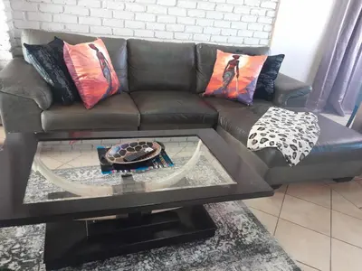 a brown leather couch with pillows and a glass table at 2 bedroom family friendly cosy & luxury home, walking distance to Doringkloof Mall in Centurion