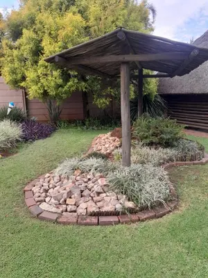 a garden with an umbrella in the grass at 2 bedroom family friendly cosy & luxury home, walking distance to Doringkloof Mall in Centurion