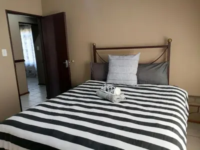 a black and white striped bed with two shoes on it at Pandleberry in Warmbaths