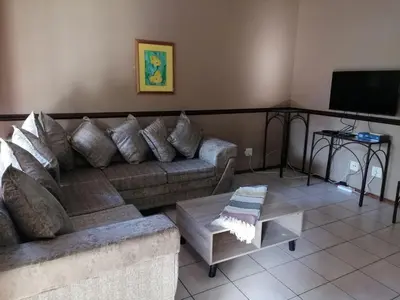 a living room with a couch and a tv at Pandleberry in Warmbaths