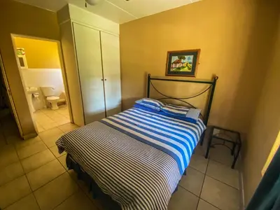 a small bedroom with a bed and a bathroom at Pandleberry in Warmbaths