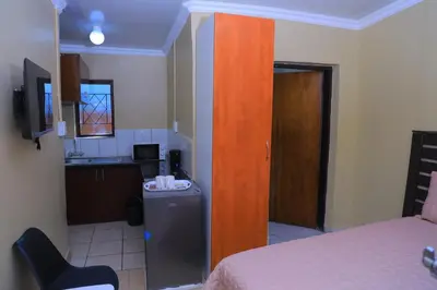 a bedroom with a bed and a kitchen with a sink at Ivy at 6 Peace Sleep in Pretoria