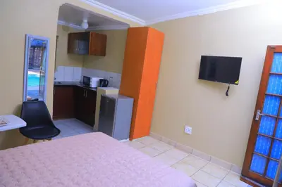 a small room with a bed and a kitchen at Ivy at 6 Peace Sleep in Pretoria