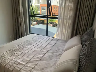 a bed in a bedroom with a large window at The Blyde Siesta in Pretoria