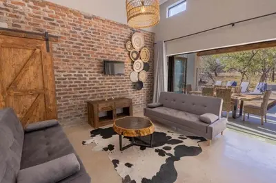 a living room with a couch and a table and a brick wall at Chui House A Bush Retreat with Pool and AC Near Kruger Gate in Marloth Park