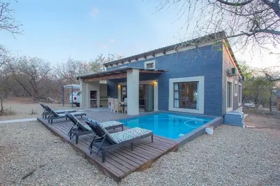 a blue house with a pool and two benches at Chui House A Bush Retreat with Pool and AC Near Kruger Gate in Marloth Park