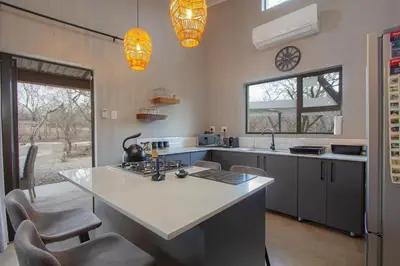 a kitchen with a table and some chairs in it at Chui House A Bush Retreat with Pool and AC Near Kruger Gate in Marloth Park