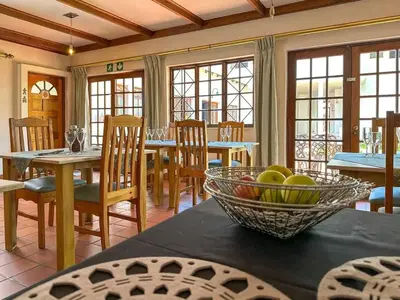 a dining room with a table with a bowl of fruit on it at Park Gables Loftus Guest House in Pretoria