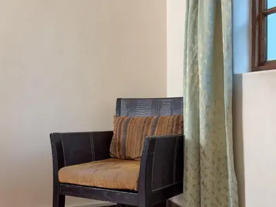 a chair sitting in a room next to a window at Park Gables Loftus Guest House in Pretoria