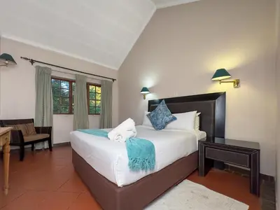 a bedroom with a bed and a table and a desk at Park Gables Loftus Guest House in Pretoria