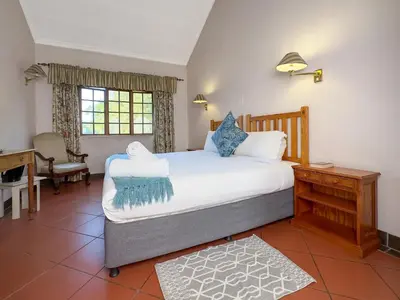 a bedroom with a large bed and a desk at Park Gables Loftus Guest House in Pretoria