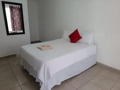 a bedroom with a white bed with a red pillow at Zindi Zindiza Lodge in Sandrivier
