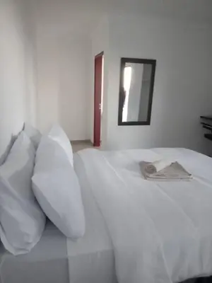 a white bed with white pillows and a mirror at Zindi Zindiza Lodge in Sandrivier