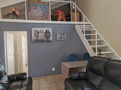 a living room with a staircase and a couch at Skuinslê in Centurion