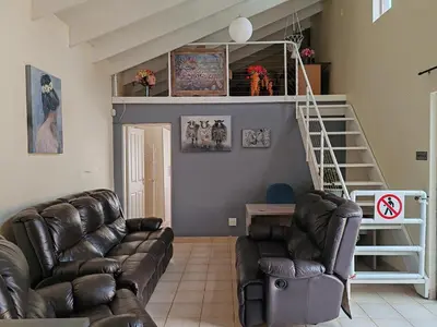 a living room with a couch and a staircase at Skuinslê in Centurion