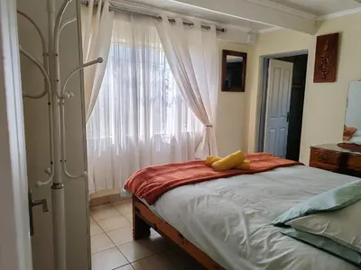 a bedroom with a bed and a large window at Skuinslê in Centurion