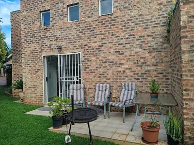 a patio with chairs and a table in front of a brick building at Skuinslê in Centurion