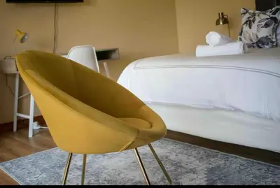 a yellow chair in a bedroom next to a bed at Private Room Kosmosdal in Centurion