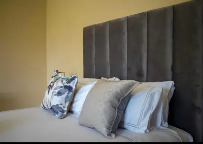 a bed with white pillows and a gray headboard at Private Room Kosmosdal in Centurion