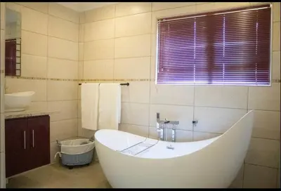 a white bath tub in a bathroom with a window at Private Room Kosmosdal in Centurion
