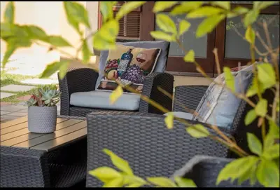 a patio with wicker chairs and a table at Private Room Kosmosdal in Centurion