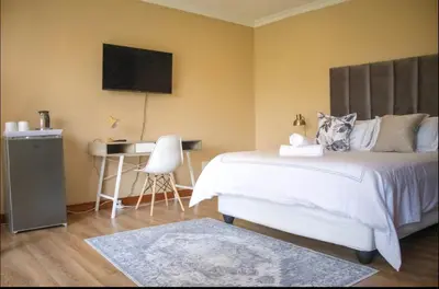 a bedroom with a bed and a desk in it at Private Room Kosmosdal in Centurion