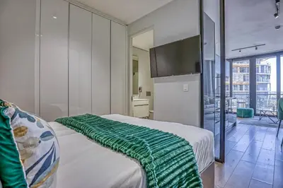 a bedroom with a bed with a green blanket on it at Celestial Cassini Cove at The Ellipse in Midrand