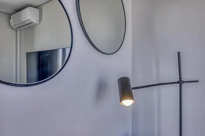 a mirror on a wall with a light and a lamp at Celestial Cassini Cove at The Ellipse in Midrand
