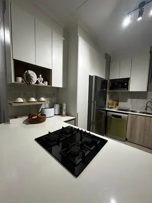 a kitchen with white cabinets and a black stove top oven at Waterfall Luxury Apartment in Midrand