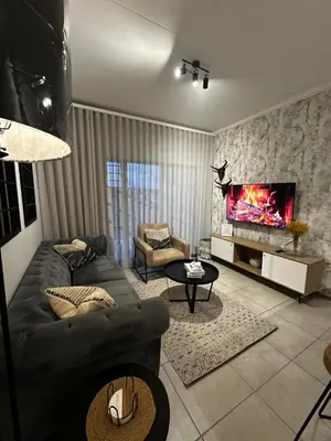a living room with a couch and a tv at Waterfall Luxury Apartment in Midrand