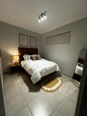 a bedroom with a large bed and a rug on the floor at Waterfall Luxury Apartment in Midrand