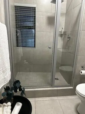 a bathroom with a shower with a glass door at Waterfall Luxury Apartment in Midrand