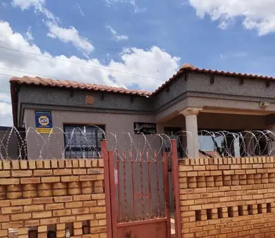 a building with a fence in front of a house at Siba's Place in Ga-Rankuwa