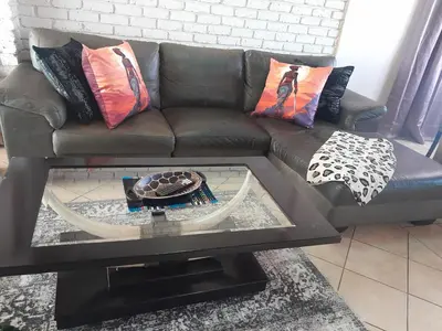 a brown couch with pillows and a table in a living room at TANS - 1 bedroom luxury & cosy home walking distance to Doringkloof Mall in Centurion