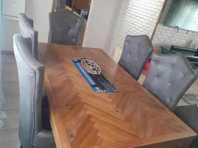 a wooden table with chairs around it with a clock on it at TANS - 1 bedroom luxury & cosy home walking distance to Doringkloof Mall in Centurion