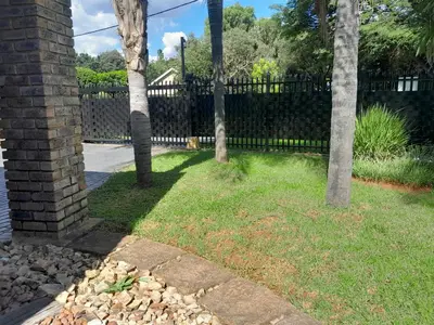 a fence in a yard with trees and grass at TANS - 1 bedroom luxury & cosy home walking distance to Doringkloof Mall in Centurion