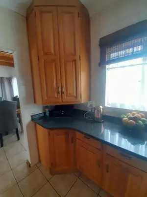 a kitchen with wooden cabinets and a bowl of fruit on the counter at TANS - 1 bedroom luxury & cosy home walking distance to Doringkloof Mall in Centurion