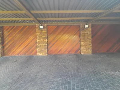 a garage with two wooden doors in a building at TANS - 1 bedroom luxury & cosy home walking distance to Doringkloof Mall in Centurion