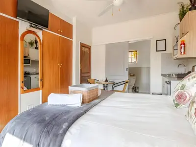 a large white bed in a room with a kitchen at Amalfi Place in Pretoria