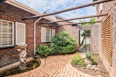 a brick house with a teddy bear statue in a courtyard at Waterfall Views in Midrand