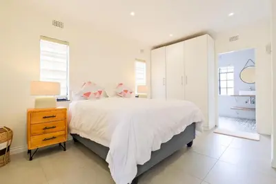 a white bedroom with a large bed and a nightstand at Waterfall Views in Midrand