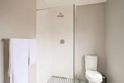 a white bathroom with a shower and a toilet at Waterfall Views in Midrand