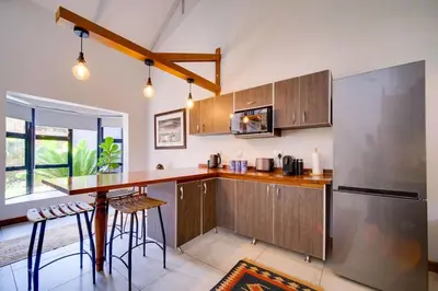 a kitchen with wooden cabinets and a bar with stools at Brooklyn Self Catering - walking distance to University of Pretoria in Pretoria
