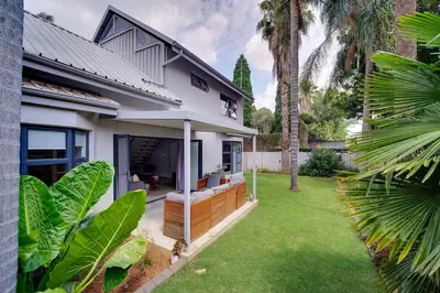 a house with a green yard with palm trees at Brooklyn Self Catering - walking distance to University of Pretoria in Pretoria