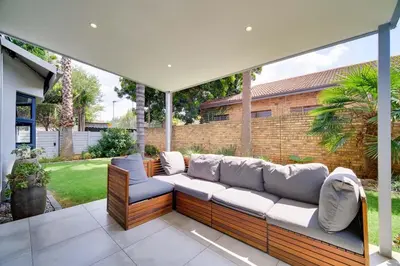 a patio with a couch under an umbrella at Brooklyn Self Catering - walking distance to University of Pretoria in Pretoria