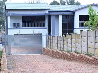a white house with a gate and a fence at El-Gibbor Residence 1 in Ermelo