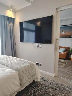 a bedroom with a large flat screen tv on the wall at Menlyn Maine Trilogy Apartment 519 in Pretoria