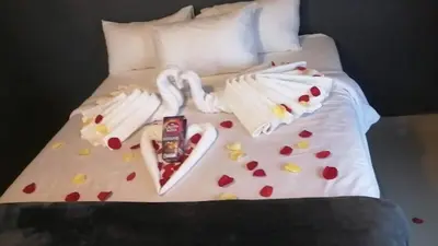 a bed with white sheets with hearts on it at The Essence Resort in Clarence