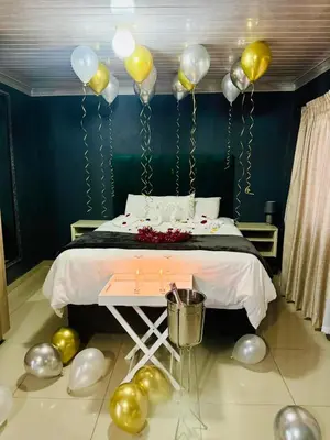 a bedroom with balloons and a bed with a table at The Essence Resort in Clarence
