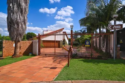 a gate in a yard with a tree and grass at The Hellens Guest House in Pretoria